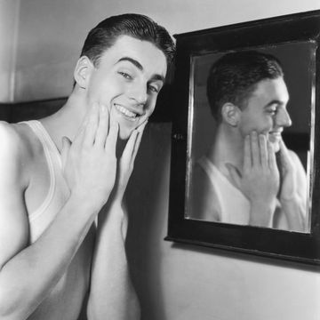 circa 1945 a young man puts his hands to his cheeks while wearing a tank top and standing next to a mirror, 1940s photo by camerique archivegetty images