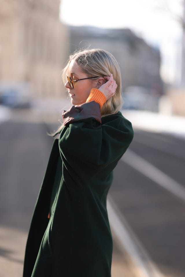 mujer con abrigo verde tocandose el pelo