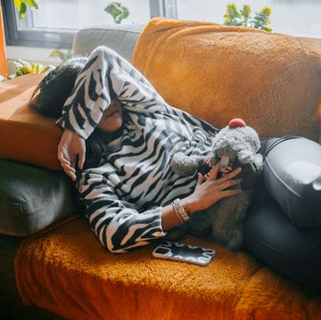 sick woman lying on orange sofa in pain