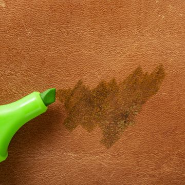 permanent green marker scribbling on red brown leather, close up