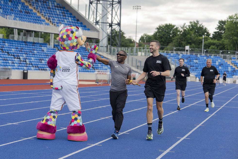 group of runners with a mascot on a running track