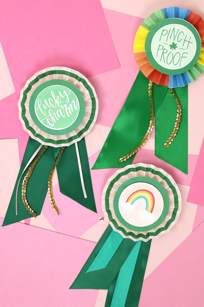 There are three paper award ribbons, one that says rainbow, one that says lucky charm, and one that says pinch proof.