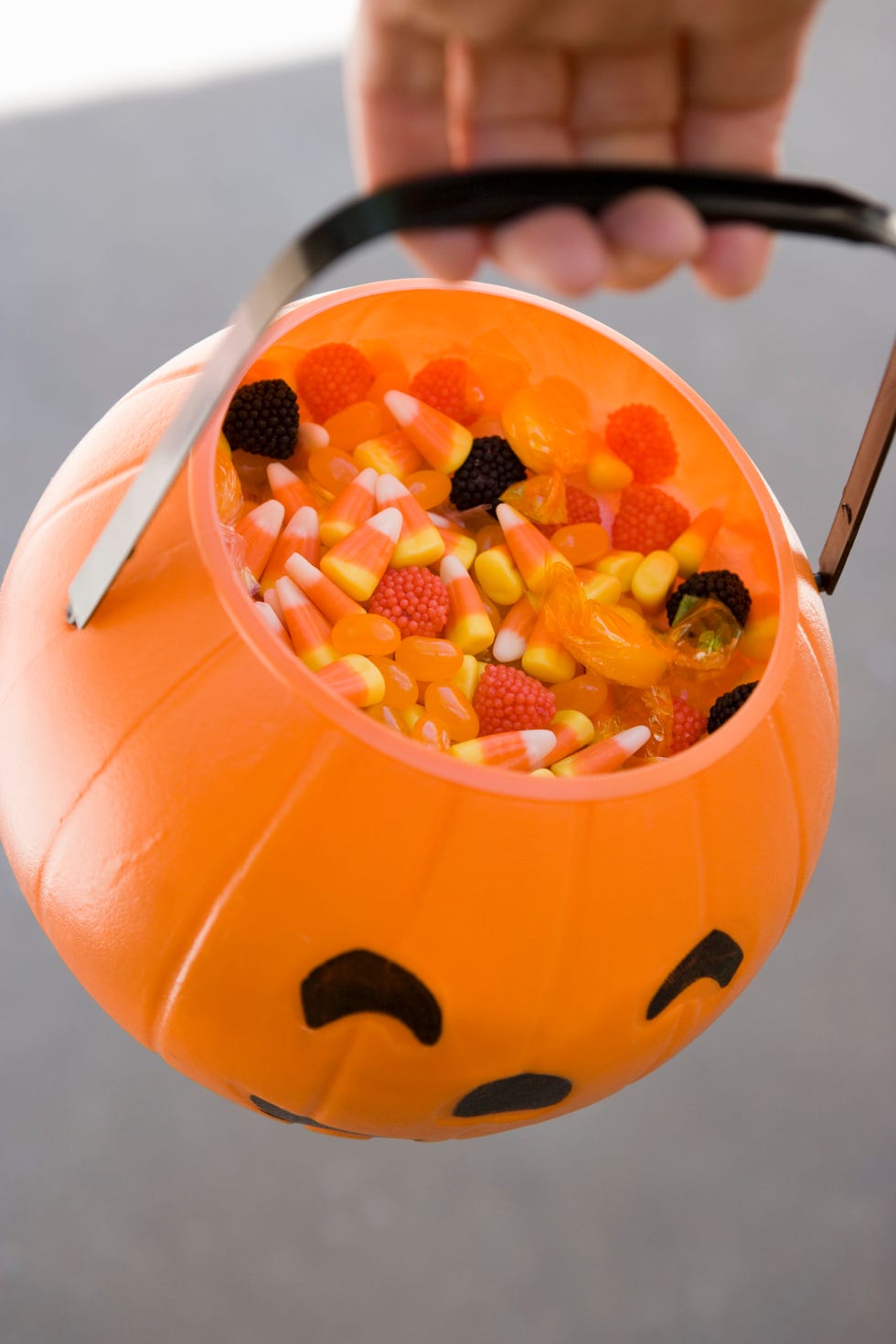 Person carrying Jack O?Lantern basket full of candy