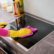 person cleaning the stove in kitchen