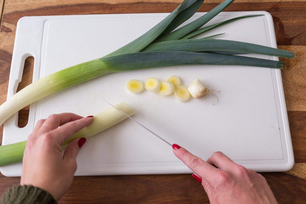 person cutting leeks on cutting board