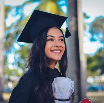 graduation picture ideas woman wearing graduation cap and gown and smiling