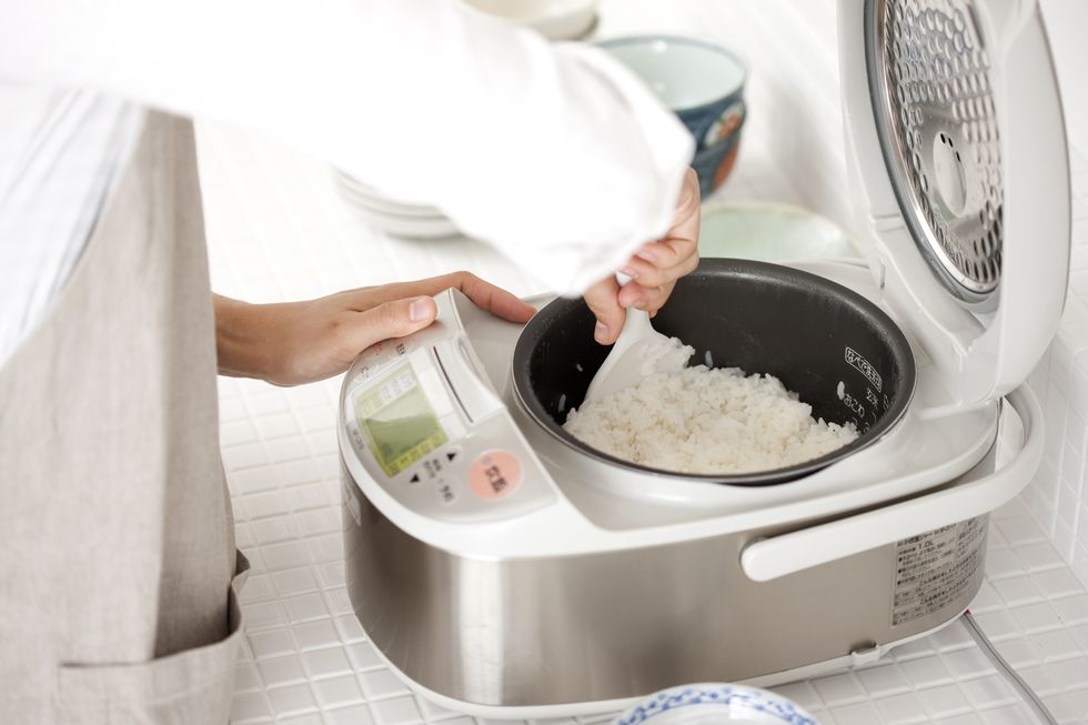 person preparing rice in a rice cooker