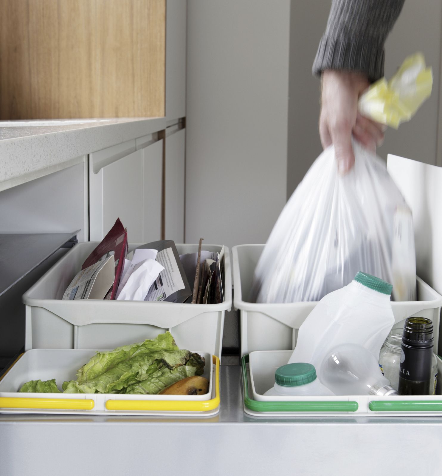 Person removing rubbish bag from waste and recycling drawer