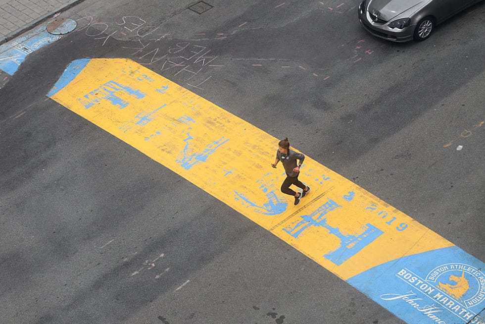 una mujer cruza en solitario la línea de meta del maratón de boston pintada en el suelo en el día en que la prueba se debía celebrar antes de ser cancelada por la covid 19