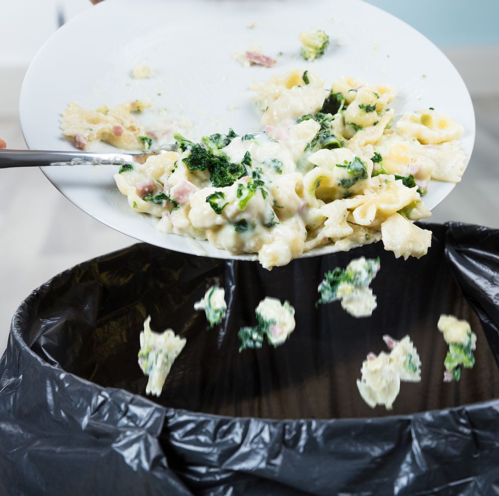 Person Throwing Cooked Pasta In Trash Bin