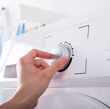 person turning button of washing machine