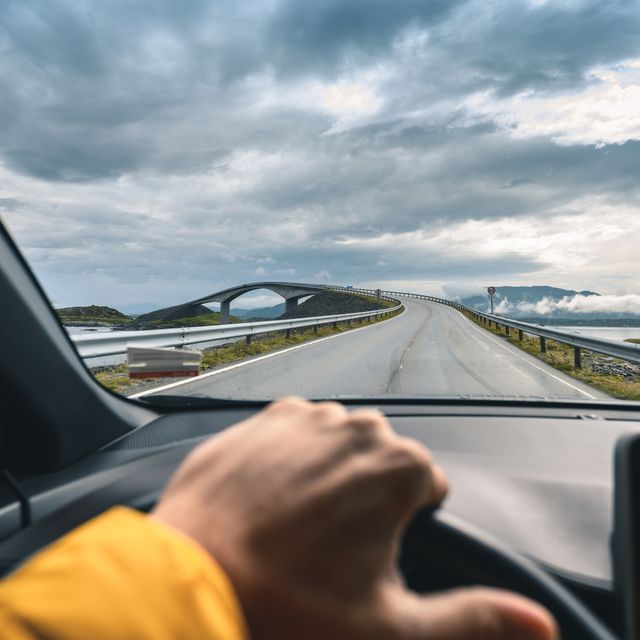 personal perspective of man driving along the atlantic ocean road, norway