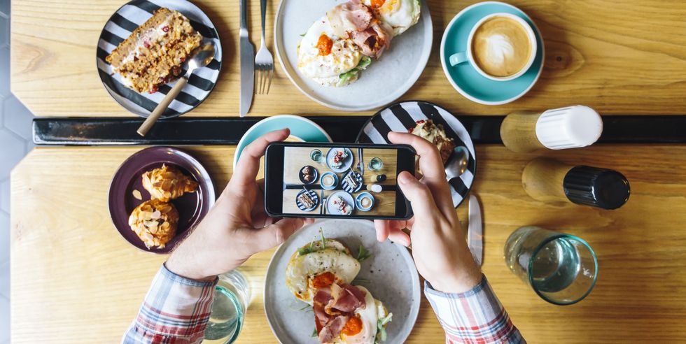 Personal perspective view of man photographing his brunch in cafe with smartphone