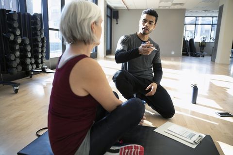 Personal trainer talking with senior woman in gym studio
