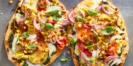 flatbread topped with pesto, corn, sliced onions, cheese, and tomatoes