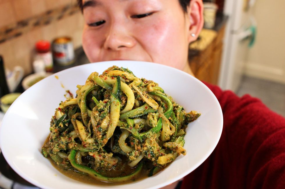june holds a white plate of pesto zoodles