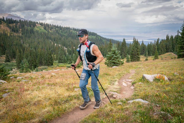 a runner wearing jeans running on a mountain trial