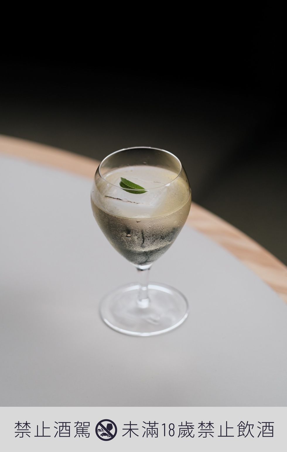 a glass with a green leaf on a white surface