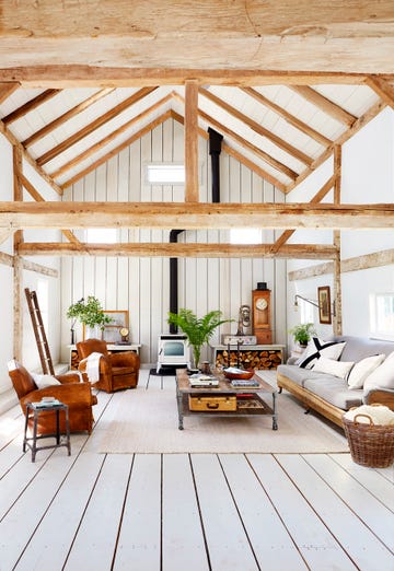 a spacious two story living room with wood ceiling beams and leather furniture