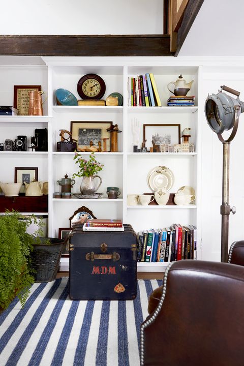 a blue and white striped rug in a white room with books and collections on shelves