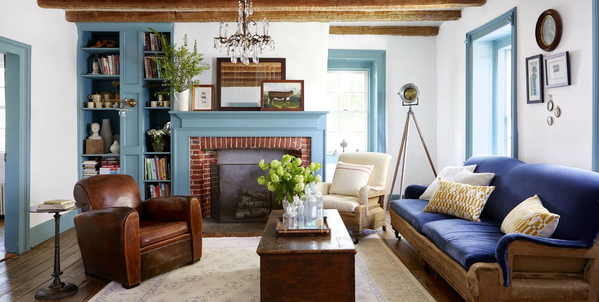 white walls wooden ceiling beams and blue painted trim in a living room with a fireplace