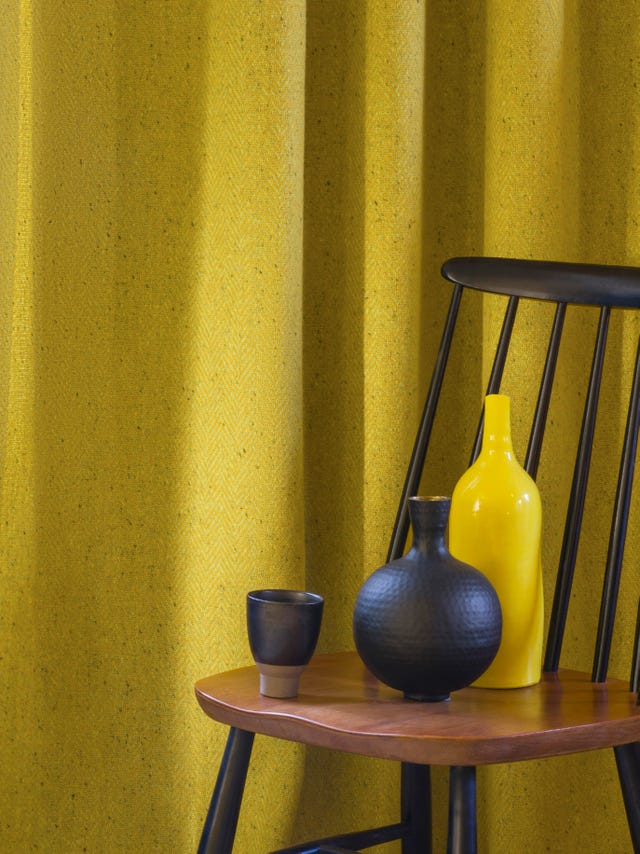 a yellow tweed fabric curtain behind a wooden chair