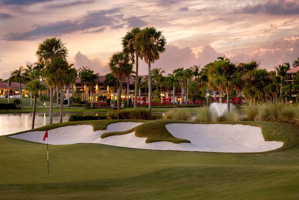 a golf course with palm trees and ponds on it