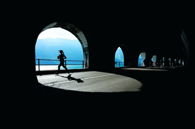 runner in a tunnel with sunlight reflecting on the lake