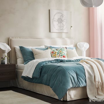 IKEA x Good Housekeeping cozy bedroom featuring a bed with decorative pillows and a pendant light