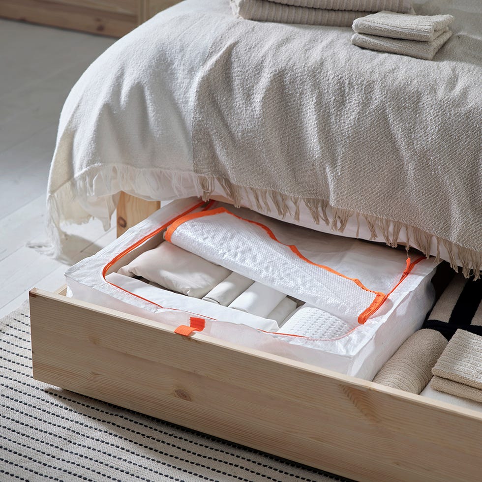 storage solution under a bed containing neatly organized linens