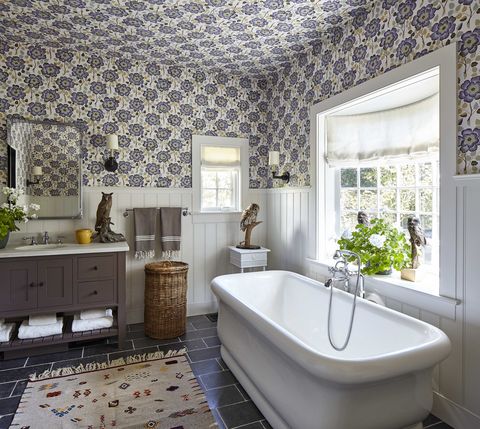 the upper walls and ceiling are covered in a flowery 
wallpaper and there is a soaking tub under the window