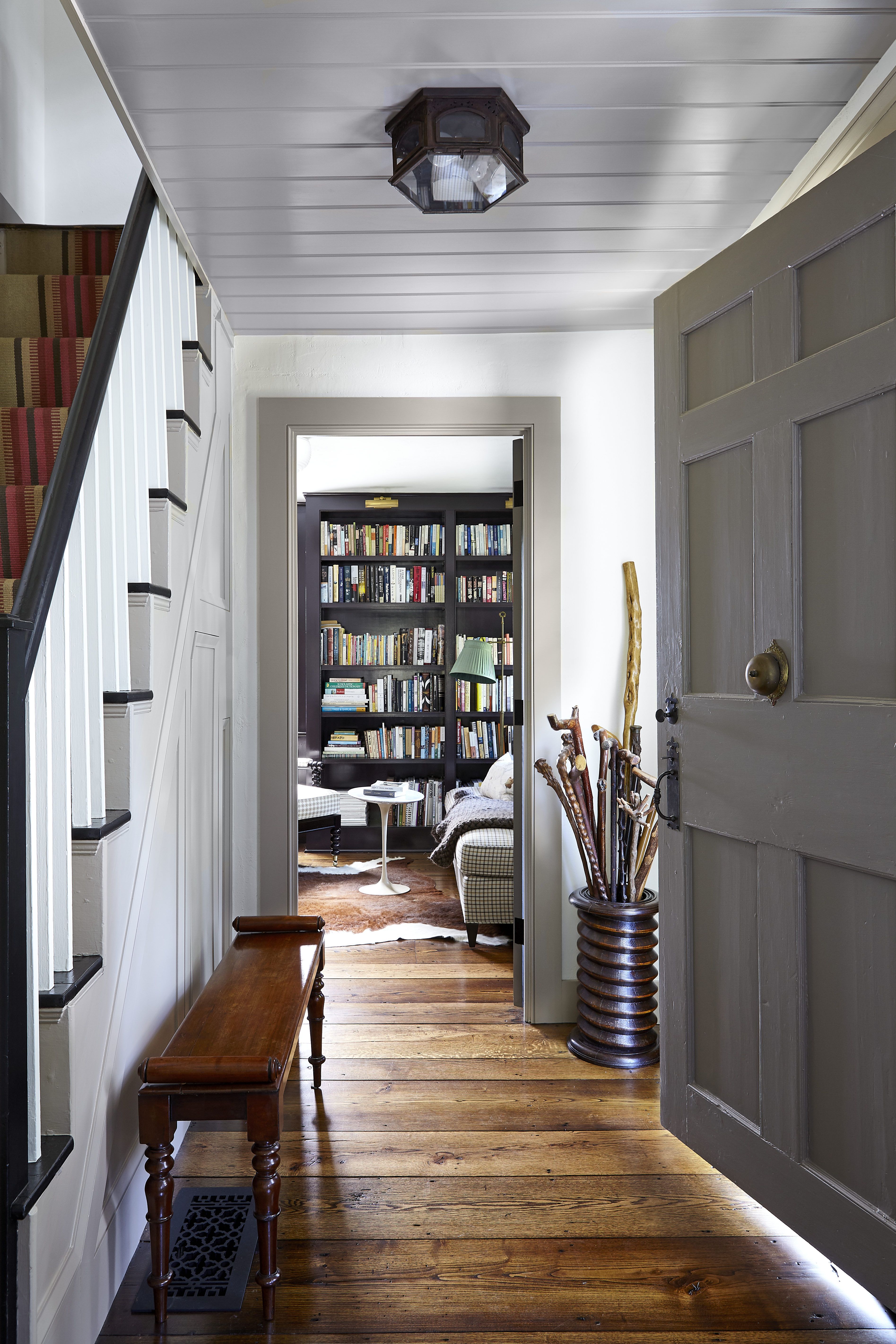 the entrance hall has wide oak flooring and a steep 18th century stairwell and cast iron bell on the door
a bookshelf is in the background