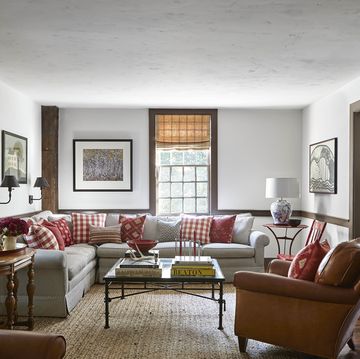 the casual living room is furnished with antique french leather armchairs and a sprawling sectional sofa covered in a vintage ticking stripe and several of the pillows were crafted with fabrics the owners picked up on their travels