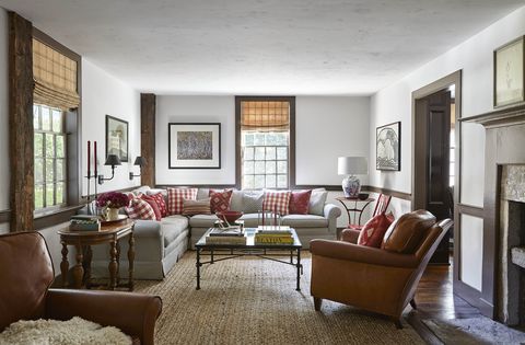 the casual living room is furnished with antique french leather armchairs and a sprawling sectional sofa covered in a vintage ticking stripe and several of the pillows were crafted with fabrics the owners picked up on their travels
