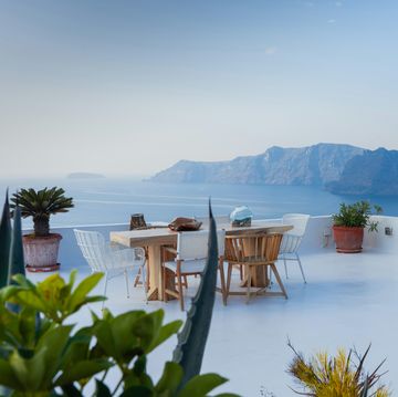 a patio with tables and chairs overlooking a body of water