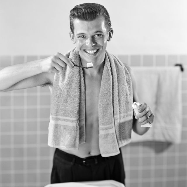 1950s smiling teenaged boy standing at bathroom sink brushing teeth looking at camera photo by cameriquegetty images