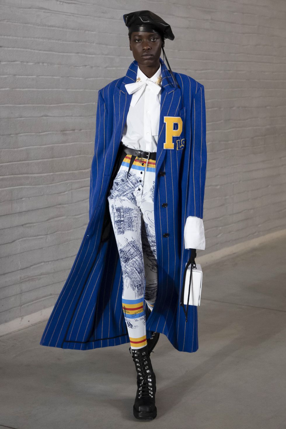 modelo desfilando para philosophy con abrigo azul de raya diplómatica, leggins, camisa con lazada, boina y botas militares