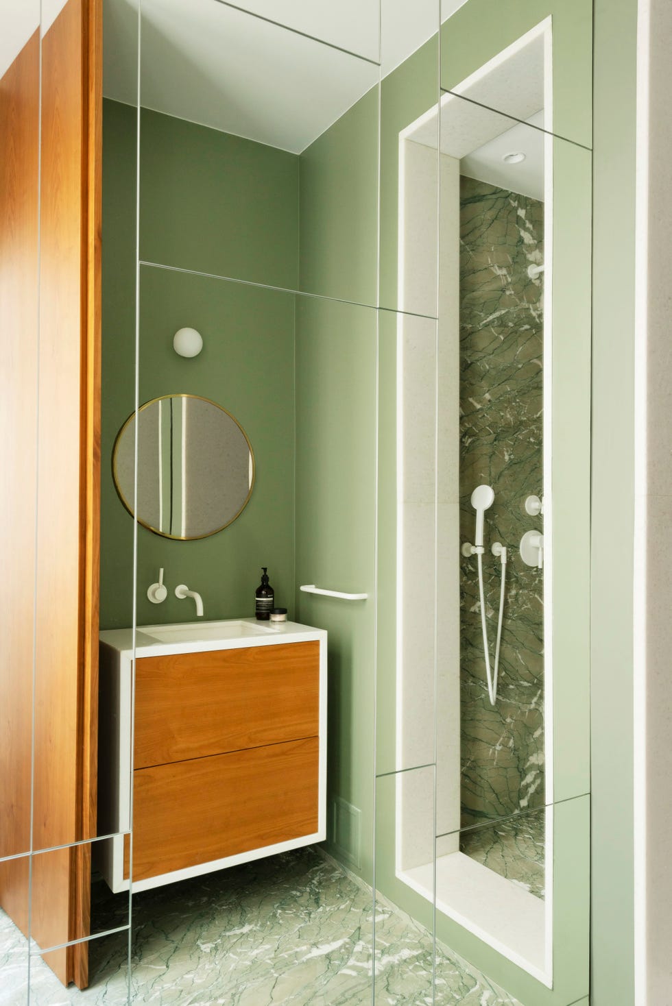 green bathroom with green marble floor and inset shower, plus wooden vanity unit