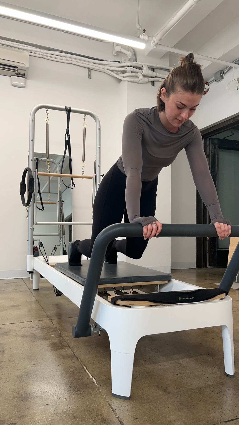 fitness editor talene performing a pilates sequence with her hands on the footbar of the allegro 2 pilates reformer machine