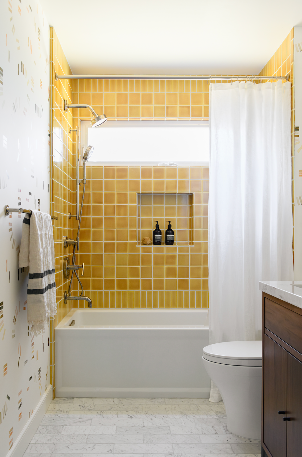 bathroom with yellow tiled shower area and white fixtures