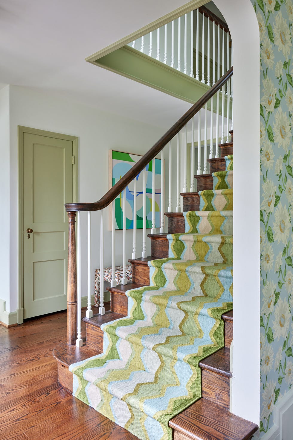 staircase with patterned runner and floral wallpaper