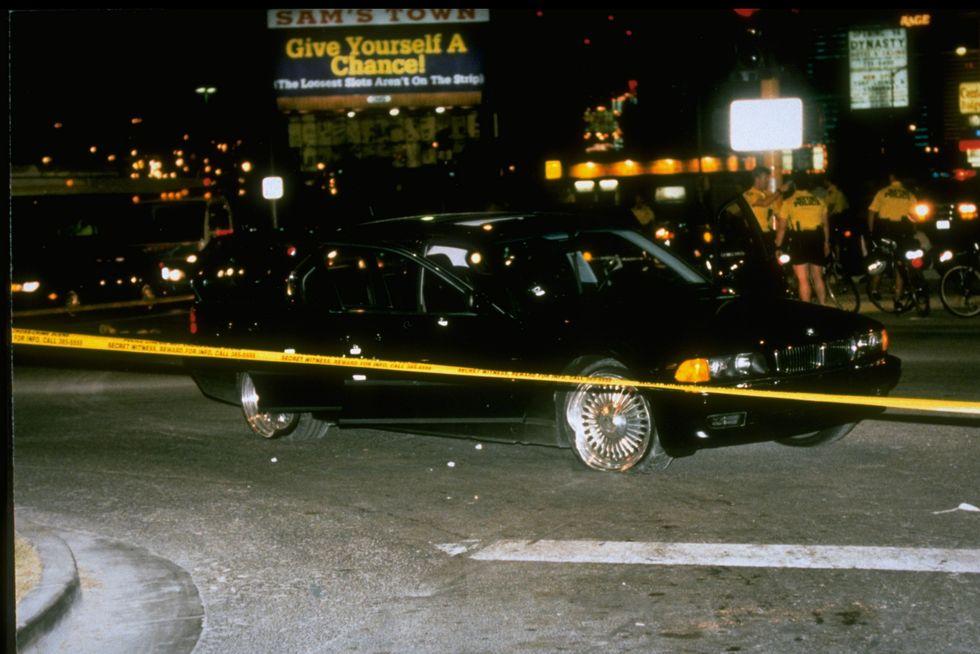 black car in which rapper tupac shakur was fatally shot by unknown driveby assassins as he was riding w friend death row records pres marion suge knight, who survived shooting, behind police tape at crime scene