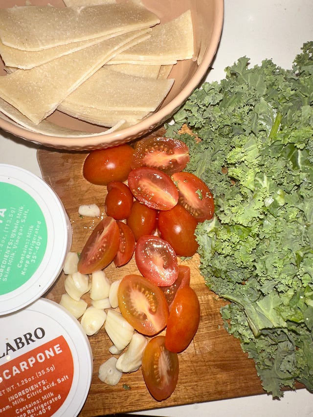 ingredients for a dish including pasta cherry tomatoes garlic kale and mascarpone cheese