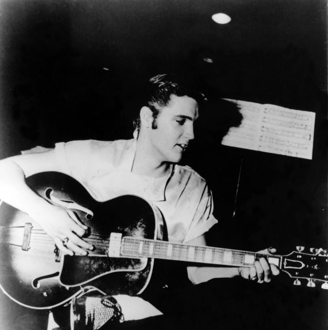 a man plays a guitar while seated