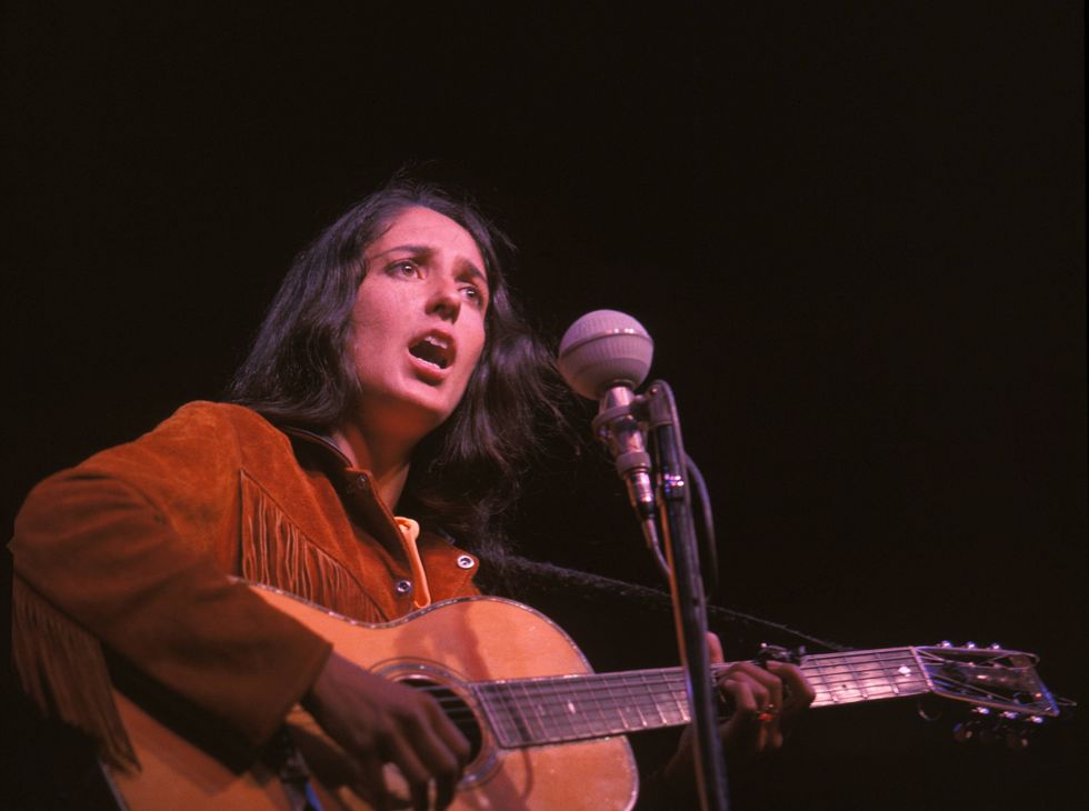 Joan Baez sings and plays guitar during a performance