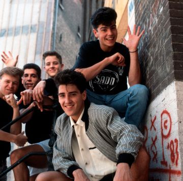 new kids on the block members donnie wahlberg, danny wood, joey mcintyre, jonathan knight, and jordan knight pose for a photo outside a brick building