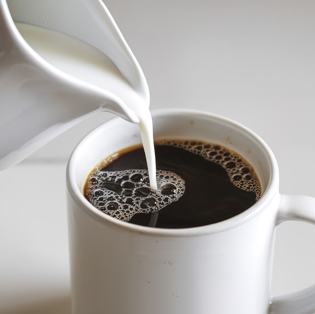 a photo of pouring milk into a glass of coffee