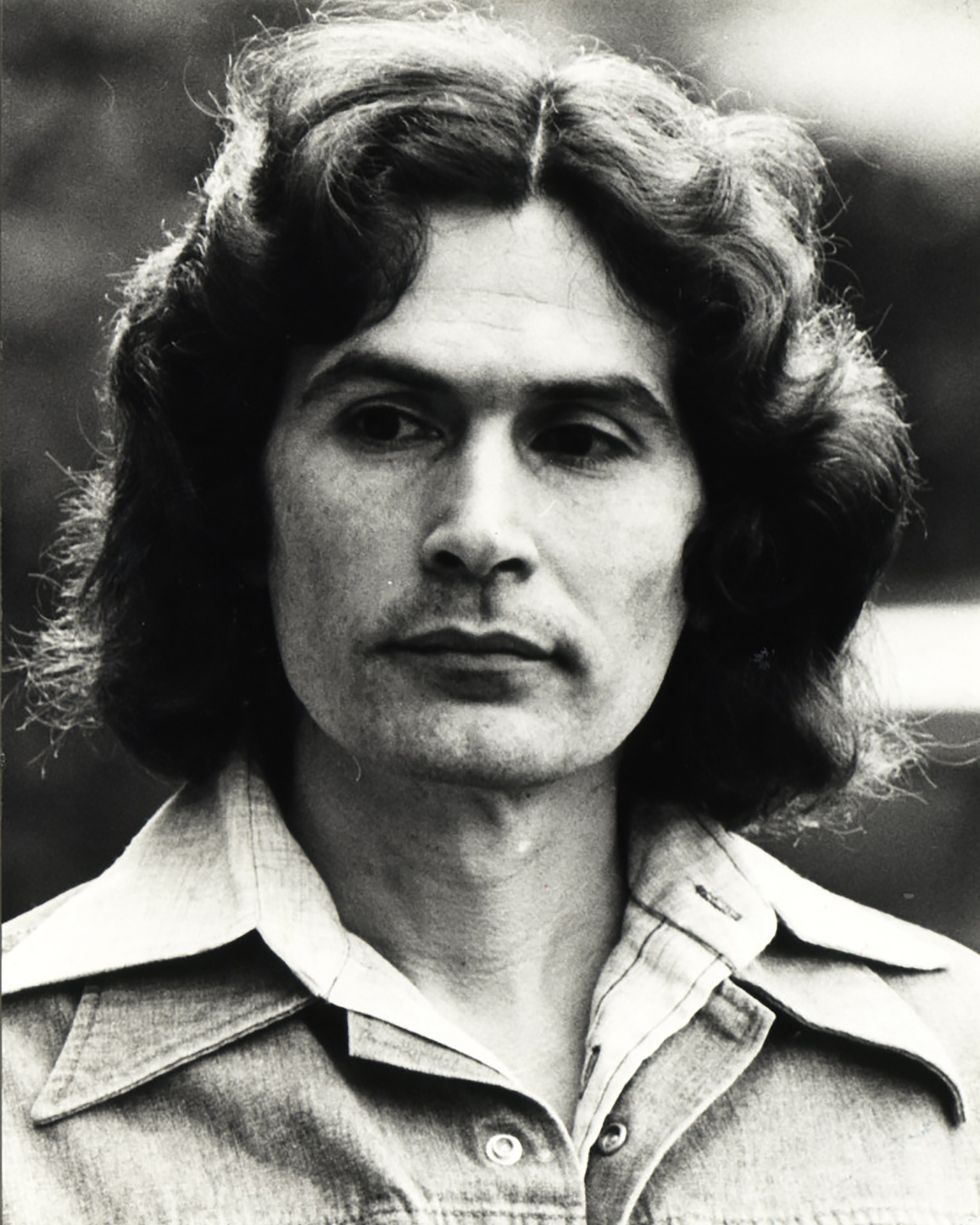 rodney alcala wearing a denim jacket and looking out of frame in a black and white photo