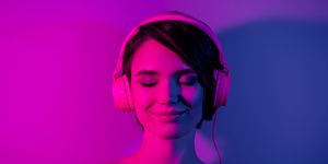 nude woman smiles with eyes closed while wearing headphones
