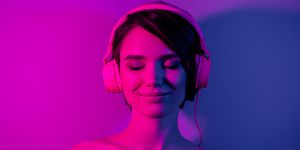 nude woman smiles with eyes closed while wearing headphones